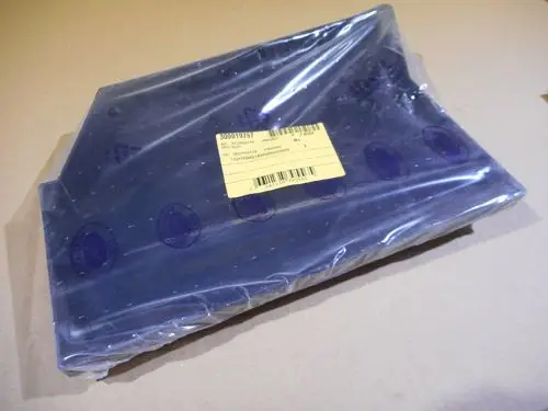 Plastikteile in Schutzfolie, versehen mit einem gelben Etikett, die zur Marke Remeha gehören. Teile scheinen für einen Luftkasten im Ölbereich gedacht zu sein.